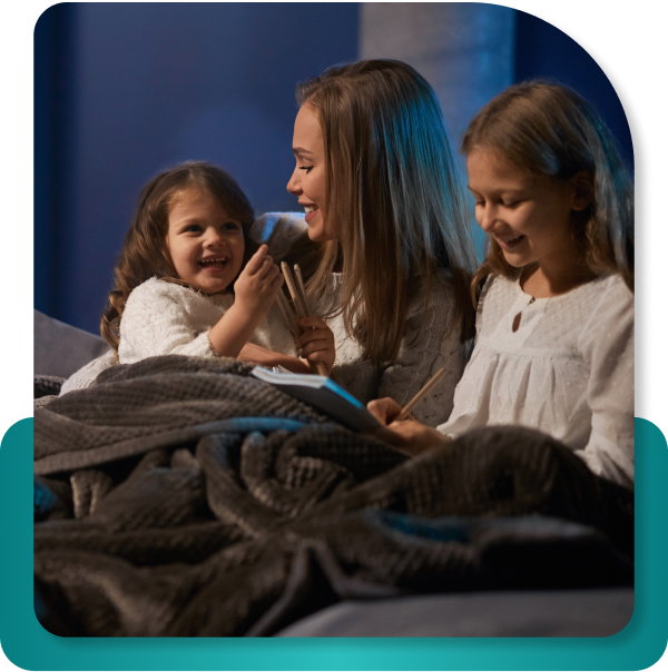 Mom and daughters sitting cozy under blanket